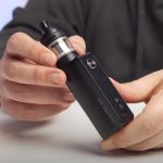A person showing a MTL vape kit on a table.